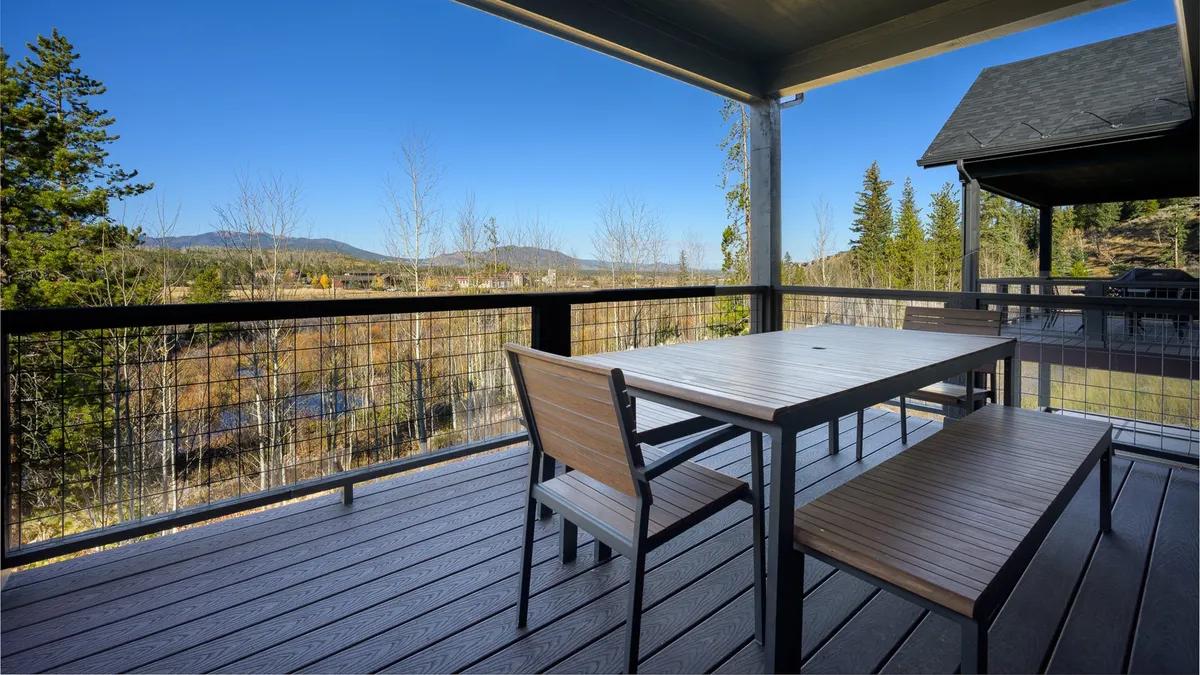 An inviting outdoor dining area on a wooden deck, with a large table and chairs overlooking breathtaking mountain scenery. The space is ideal for morning coffee, al fresco dining, or evening gatherings under the stars.