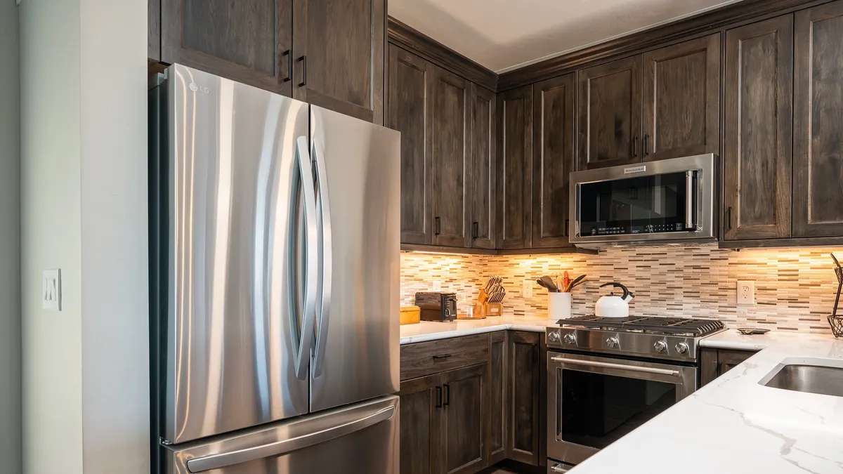 A spacious, light-filled kitchen with gleaming stainless steel refrigerator and a modern stove/oven combo set against a stylish decorative backsplash. Wide countertops provide ample space for meal prep, and the overall layout is practical yet inviting. Subtle signs of entertaining and family gatherings hint at the kitchen's role as the heart of the home.